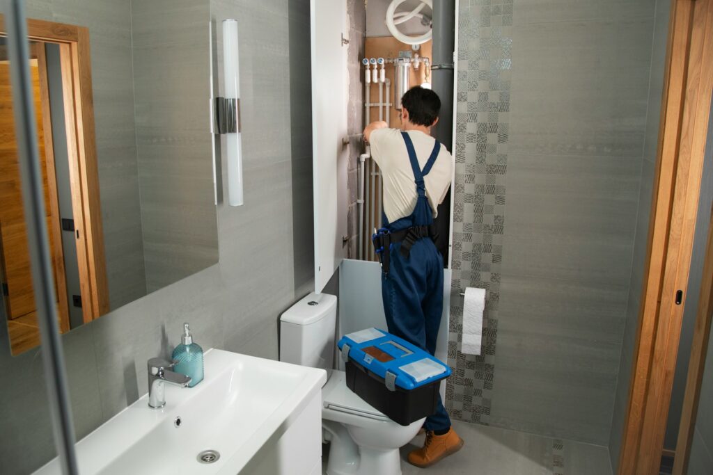 Plumber installing pipes in an open bathroom wall during a partial repipe.